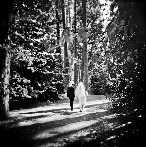 black and white photo - beautiful image of the bride and groom taking a walk through the woods - photo by New Mexico based wedding photographers Twin Lens